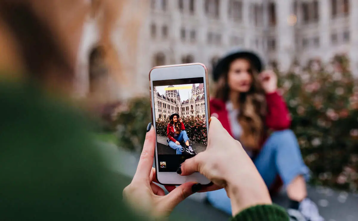 Femme prise en photo par une autre femme avec un téléphone.